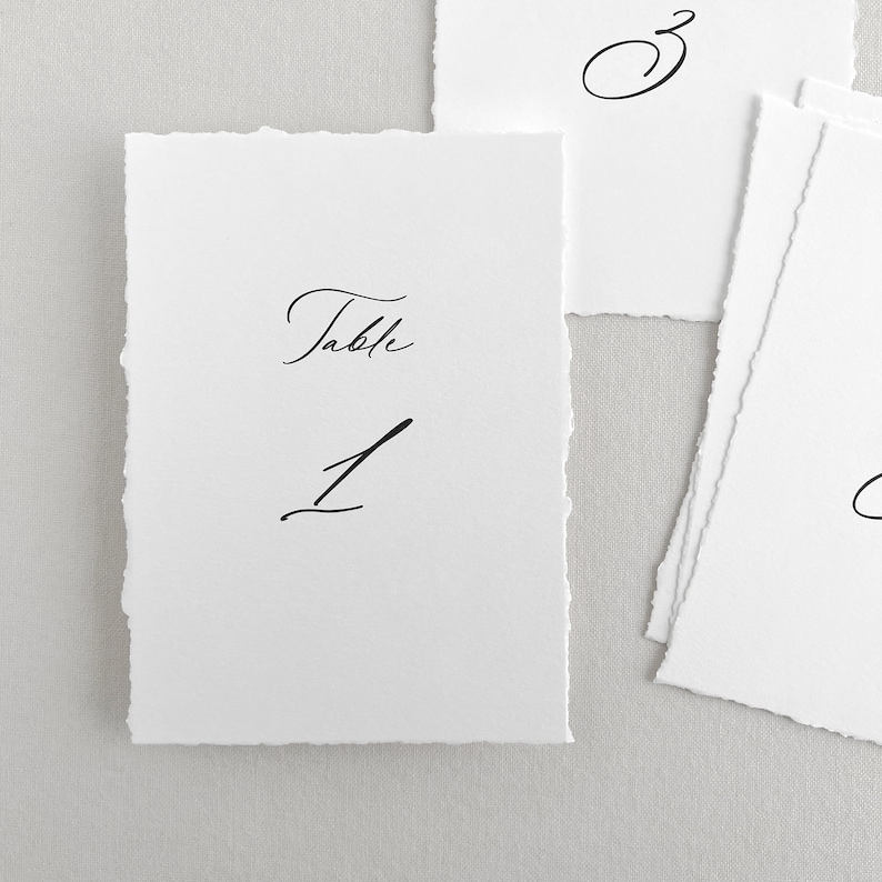 Pu&ograve; includere: Carta bianca con il testo "Tavolo 1" scritto in calligrafia nera.