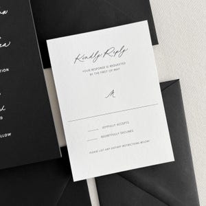 K&ouml;nnte beinhalten: Eine wei&szlig;e RSVP-Karte mit schwarzem Text. Die Karte lautet "Kindly Reply" und enth&auml;lt einen Abschnitt, in dem die G&auml;ste angeben k&ouml;nnen, ob sie "Joyfully Accept" oder "Regretfully Decline". Die Karte enth&auml;lt auch einen Platz f&uuml;r die G&auml;ste, um etwaige di&auml;tetische Einschr&auml;nkungen aufzulisten.