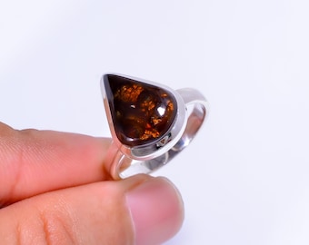 May include: A silver ring featuring a teardrop-shaped gemstone with a dark brown and orange pattern. The ring's band is a polished silver, and the gemstone is set in a bezel setting.