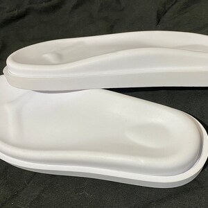 May include: Two white plastic footbeds for sandals or slippers. The footbeds have a raised, contoured design for comfort.
