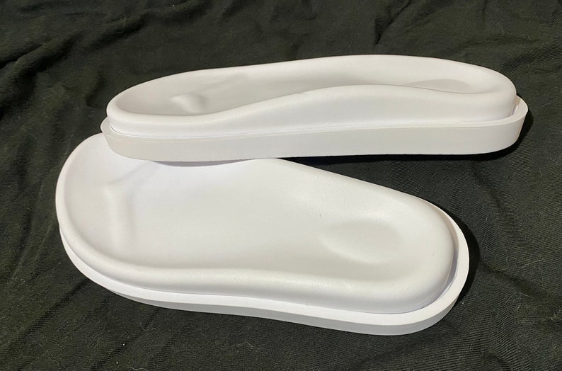 May include: Two white plastic footbeds for sandals or slippers. The footbeds have a raised, contoured design for comfort.