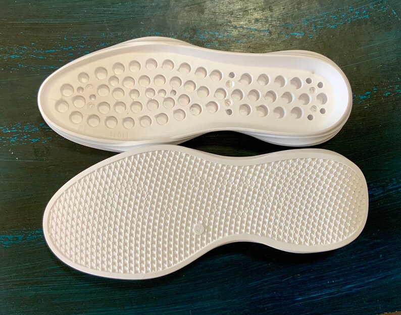 May include: Two white shoe soles, one with a circular pattern and the other with a diamond pattern.