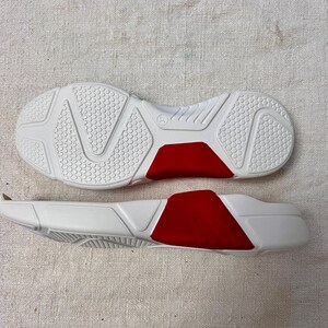 May include: A pair of white shoe soles with red accents. The soles are made of a textured rubber material and have a raised pattern on the bottom.