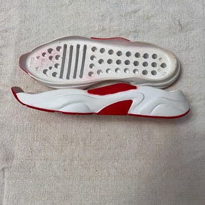 May include: White and red shoe sole with a textured bottom and a row of small holes. The sole is designed for a shoe with a thick, chunky platform.