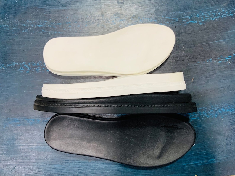 May include: Three layers of white and black shoe soles. The top layer is white and the bottom two layers are black.
