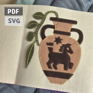 Peut inclure: Page de livre en feutre faite à la main avec un vase beige orné d'un cheval et d'une étoile marron foncé. Le vase a des anses marron foncé et est bordé de fil doré. Des feuilles en feutre vert et le texte "PDF SVG" sont également visibles.