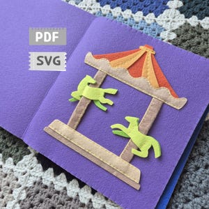 Peut inclure: Scène de manège en feutre sur fond violet. Le manège a une base beige, des poteaux marron et un toit orange et jaune coloré. Deux chevaux verts sont attachés aux poteaux. Les textes "PDF" et "SVG" sont dans le coin supérieur gauche.