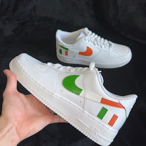 May include: White leather sneakers with a green, orange, and white design on the side. The design resembles the Irish flag.