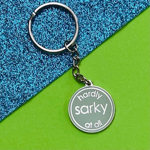 May include: A silver keychain with a round charm that says "hardly sark at all" in white lettering.