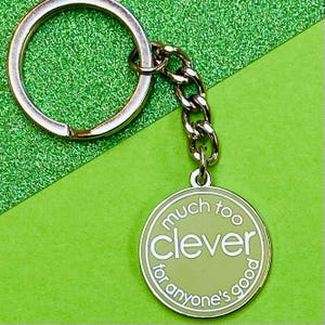 May include: A silver keyring with a round, light green charm that says "much too clever for anyone's good".