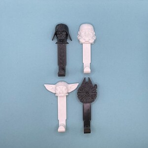 Peut inclure: Ensemble de cinq crochets muraux représentant des personnages de Star Wars. Les crochets sont en plastique blanc et noir et représentent Dark Vador, un Stormtrooper, Yoda et le Faucon Millenium.