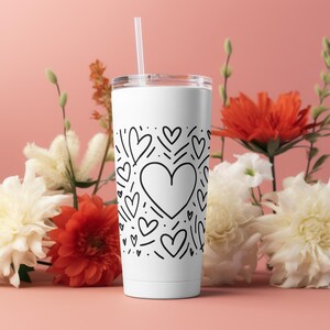 May include: White tumbler with a black and white design of hearts and swirls. The tumbler has a lid and a straw.