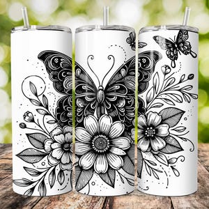 Könnte beinhalten: Drei Edelstahlbecher mit einem schwarz-weißen Design aus einem Schmetterling und Blumen. Der Schmetterling befindet sich in der Mitte des Designs und hat komplizierte Details. Die Blumen sind um den Schmetterling herum angeordnet und haben ein einfaches Design.