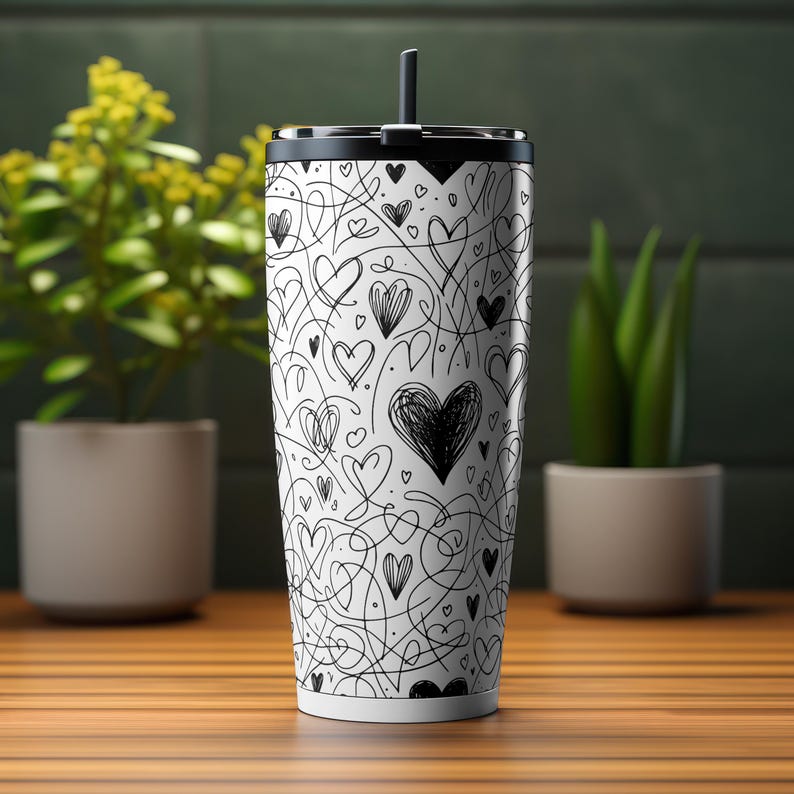 May include: A white stainless steel tumbler with a black lid and a black straw. The tumbler is covered in a black and white pattern of hearts and swirls.
