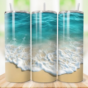 May include: Three stainless steel tumblers with a beach scene design. The design features a turquoise ocean with white waves washing onto a sandy shore. Each tumbler has a clear lid and a reusable straw.