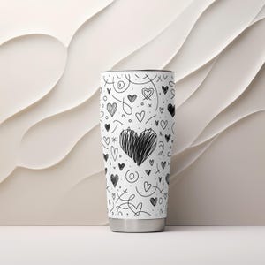 May include: White stainless steel tumbler with a black and white doodle pattern of hearts and swirls.