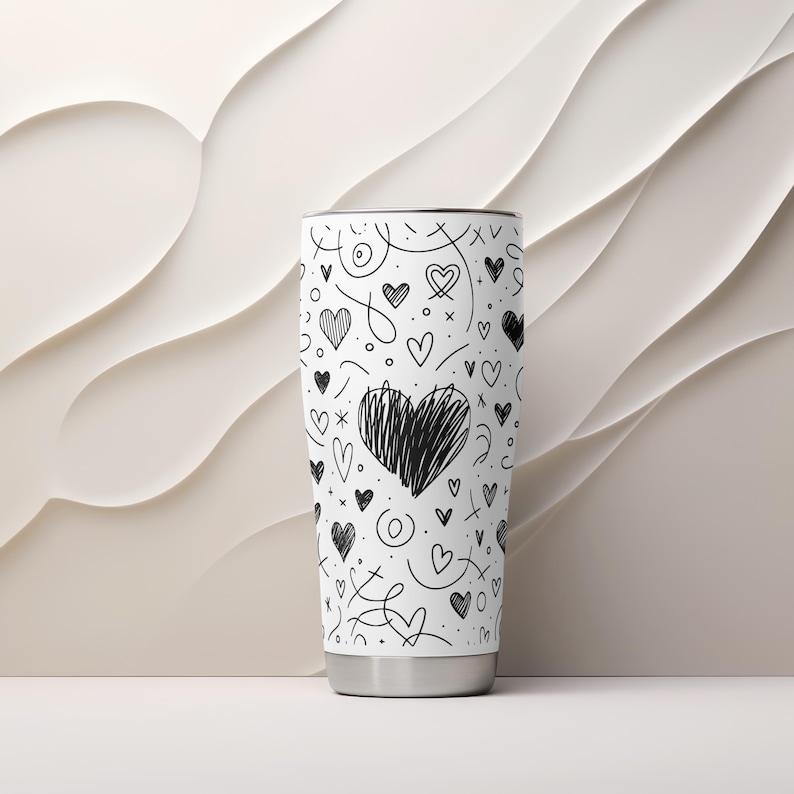 May include: White stainless steel tumbler with a black and white doodle pattern of hearts and swirls.