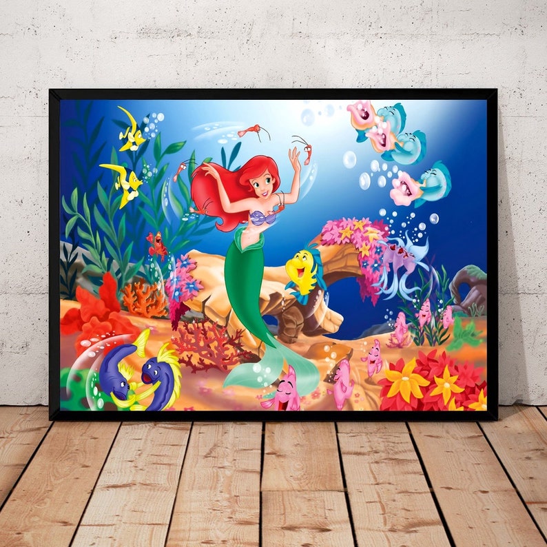 Puede incluir: Una ilustraci&oacute;n enmarcada de Ariel, la Sirenita, nadando en el oc&eacute;ano. Est&aacute; rodeada de corales coloridos, peces y burbujas.