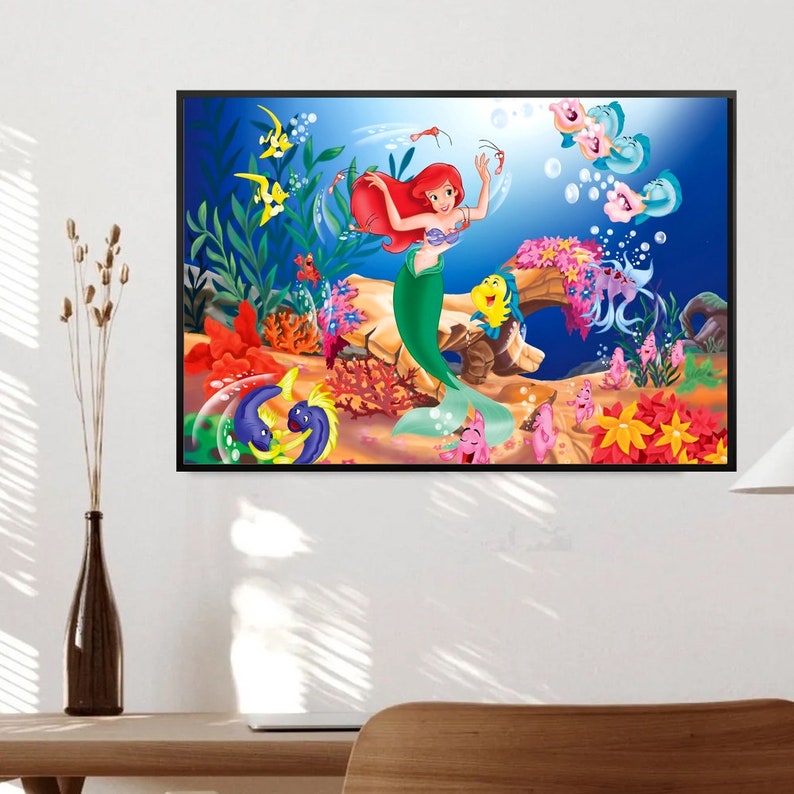 Puede incluir: Una ilustraci&oacute;n colorida de Ariel, la Sirenita, nadando en el oc&eacute;ano con otros peces. Lleva una cola verde y tiene el pelo rojo. El fondo es un oc&eacute;ano azul con arrecifes de coral y otras criaturas marinas.