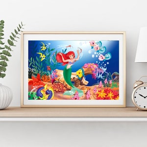 Puede incluir: Una ilustraci&oacute;n enmarcada de Ariel, la Sirenita, nadando en el oc&eacute;ano con peces y corales coloridos. Lleva su caracter&iacute;stico sujetador de concha p&uacute;rpura y su cola verde.