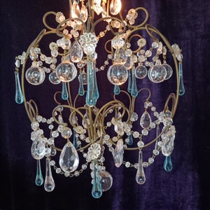 May include: A vintage chandelier with a gold metal frame and crystal teardrop pendants. The chandelier has a blue and clear crystal design.