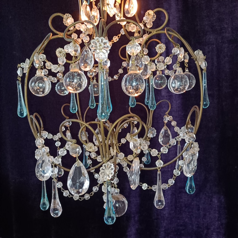 May include: A vintage chandelier with a gold metal frame and crystal teardrop pendants. The chandelier has a blue and clear crystal design.