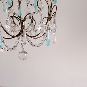 May include: A crystal chandelier with a metal frame and blue and clear glass teardrop-shaped crystals.