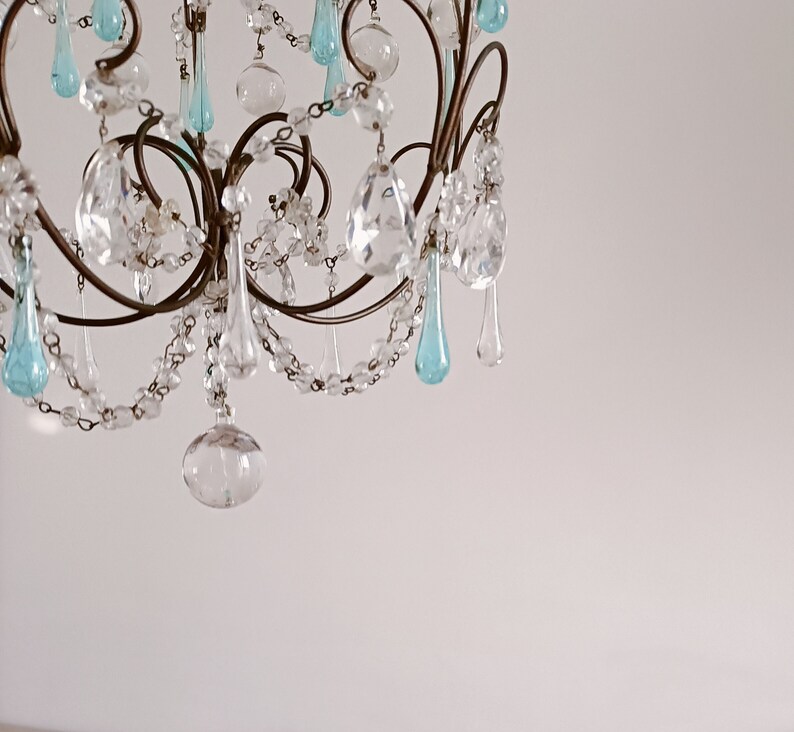 May include: A crystal chandelier with a metal frame and blue and clear glass teardrop-shaped crystals.