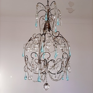 May include: A large, ornate chandelier with a metal frame and many crystal drops. The chandelier has a blue and clear glass design.