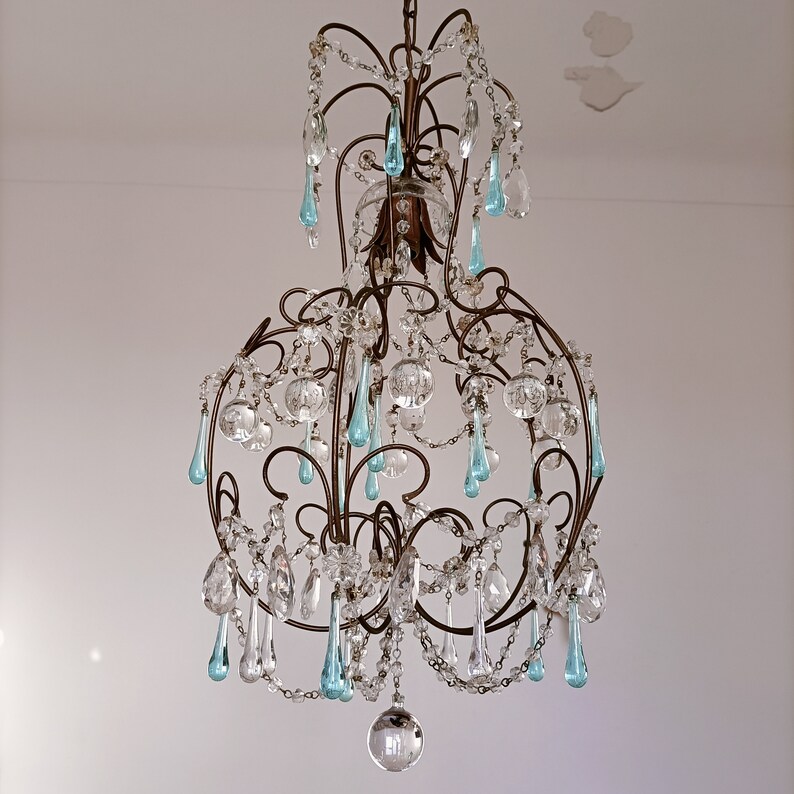 May include: A large, ornate chandelier with a metal frame and many crystal drops. The chandelier has a blue and clear glass design.