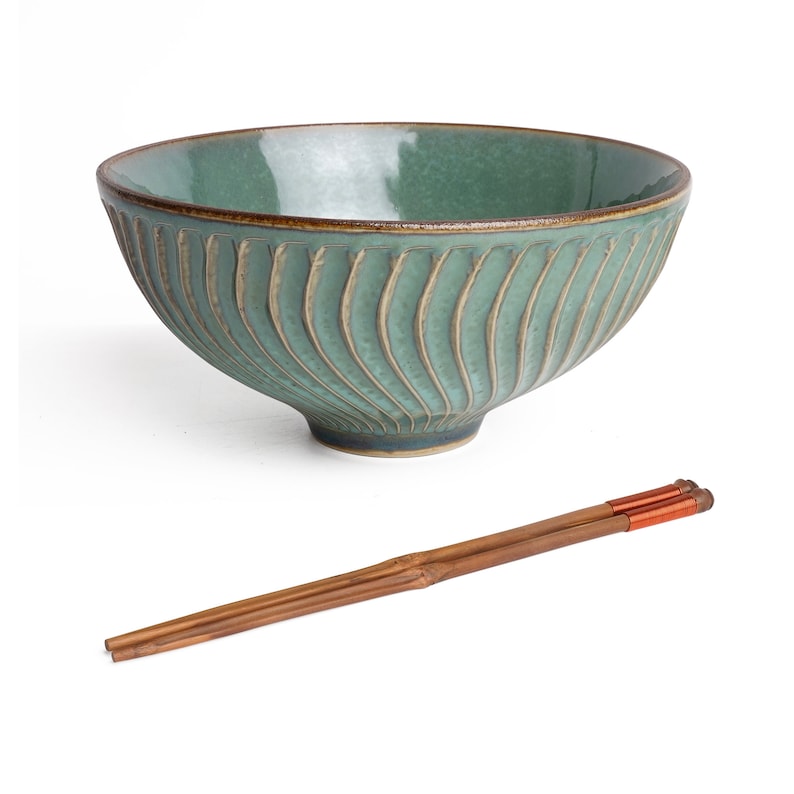 May include: A green ceramic bowl with a textured, wavy design and a pair of brown wooden chopsticks.