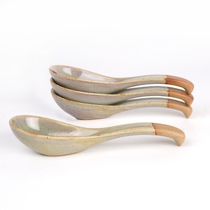 May include: Four ceramic soup spoons with a light green glaze and brown handles. The spoons are stacked on top of each other.