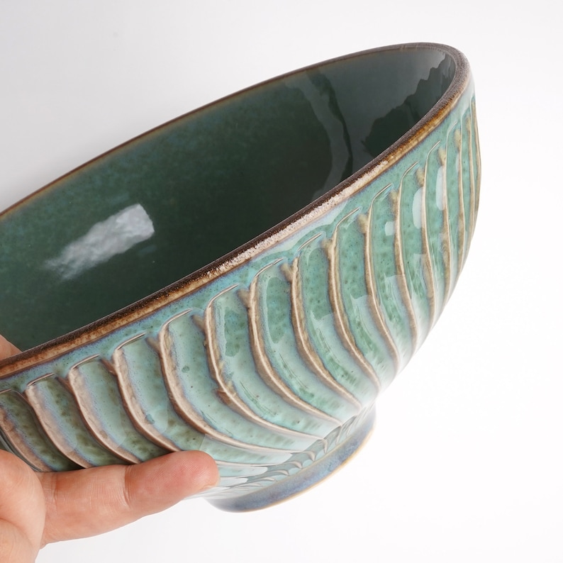 May include: A large, green ceramic bowl with a textured, wavy design. The bowl has a brown rim and a glossy finish.