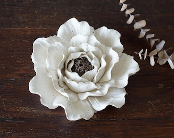 May include: White ceramic flower incense burner with a speckled finish. The flower has multiple layers of petals and a small hole in the centre for incense sticks.