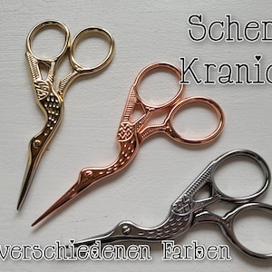Könnte beinhalten: Drei Paare dekorativer Scheren mit Kranich-förmigen Griffen. Die Scheren sind golden, roségold und silber.
