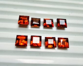 May include: Ten square-shaped, orange-brown gemstones. The gemstones are arranged in two rows of five.