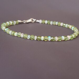 May include: A delicate bracelet made with alternating green peridot and white opal beads. The bracelet is secured with a silver clasp.