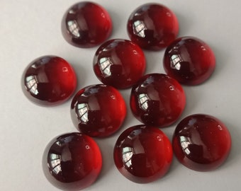 May include: Ten round, red, cabochon gemstones. The gemstones are smooth and polished.