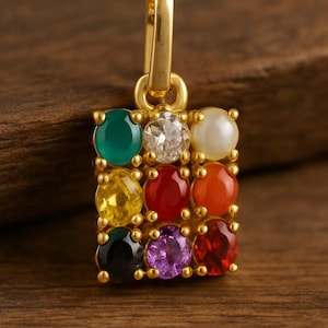 May include: Gold pendant with a square design, featuring nine colorful gemstones. The gemstones include green, clear, white, yellow, red, orange, black, purple, and red. The pendant has a gold loop for hanging.