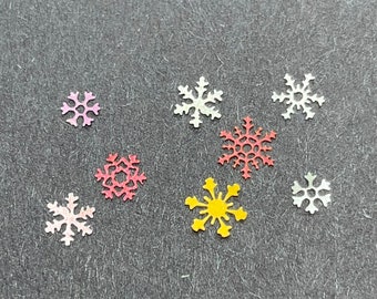 May include: Assortment of paper snowflakes in various colours, including white, pink, red, and yellow. The snowflakes are cut from paper and have a delicate, intricate design.