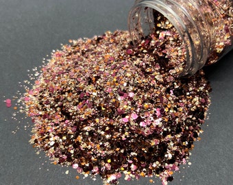 May include: A pile of pink, gold, and brown glitter spills out of a clear jar. The glitter is a mix of different sizes and shapes.