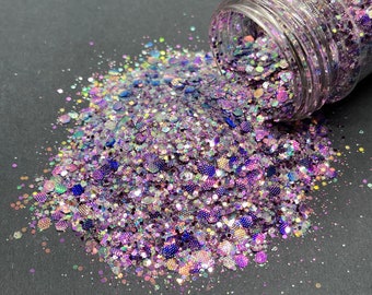 May include: A jar of iridescent purple, blue, and silver glitter spills out onto a black surface. The glitter is a mix of different sizes and shapes, creating a sparkly and colorful effect.