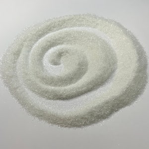 May include: A close-up of a pile of white glitter, arranged in a spiral pattern.