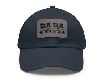 Könnte beinhalten: Marineblaue Baseballkappe mit gebogenem Schirm. Die Kappe hat ein rechteckiges Patch mit dem Wort "PAPA" in fetten Buchstaben. Unter dem Wort "PAPA" stehen die Namen "Sherry", "Mark" und "Sila".