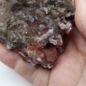 May include: A cluster of gray, white, and red crystals with a rough, textured surface.