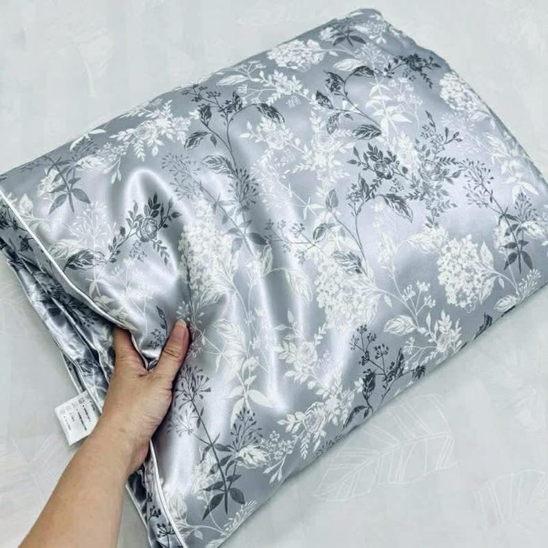 Peut inclure: Une housse de couette gris argent&eacute; pli&eacute;e avec un imprim&eacute; botanique blanc et gris fonc&eacute; repr&eacute;sentant diverses fleurs, feuilles et tiges. Le tissu pr&eacute;sente un &eacute;clat satin&eacute; lisse et comprend une &eacute;tiquette d'entretien blanche sur le bord.