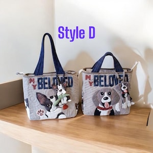 May include: Two gray quilted tote bags with navy blue handles. Each bag features a dog design and the text "MY BELOVED". One bag has a black and white dog, the other has a brown and white dog. Each bag has a dog charm.
