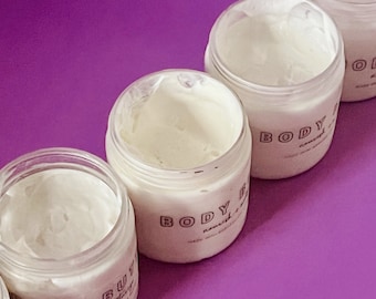 May include: Four glass jars filled with white body butter, labeled "BODY BUTTER nourish"