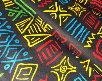 Tela Ankara con vibrantes motivos culturales: verde, azul, rojo y amarillo sobre negro