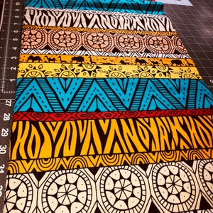 Könnte beinhalten: Ein farbenfroher Stoff mit einem sich wiederholenden Muster aus geometrischen Formen und Tierdrucken. Der Stoff ist in verschiedenen Farben gehalten, darunter Rot, Gelb, Blau, Schwarz und Weiß. Der Stoff ist perfekt für Bastelprojekte wie Quilts, Kissen und Taschen.